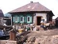 old wooden dirty house in the Siberian untidy village with garbage and the scattered things in the unkempt yard