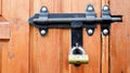 Old wooden door with a black metal bolt. Close up view of a lock and latch on a wooden door. Rustic wooden metal door latch. This Royalty Free Stock Photo