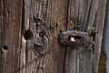 Old wooden door, closeup of door handle, closing mechanism. Rusted iron components and old creased wood surface