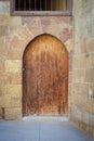 Old wooden door framed by arched bricks stone wall, Darb al Ahmar district, Old Cairo, Egypt