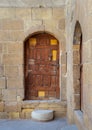 Old wooden door framed by arched bricks stone wall, Darb al Ahmar district, Old Cairo, Egypt