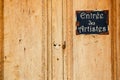 Old wooden door and metal plate with text `entry of the artists` Royalty Free Stock Photo