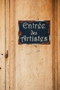 Old wooden door and metal plate with text `entry of the artists` Royalty Free Stock Photo