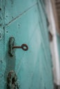 Old wooden door painted with cracked green paint and rusty key in the keyhole Royalty Free Stock Photo