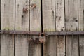 Old wooden door with a steel rusty lock. Farm gate from planks with an old padlock. Security.ancient values Royalty Free Stock Photo