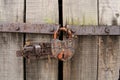 Old wooden door with a steel rusty lock. Farm gate from planks with an old padlock. Security.ancient values Royalty Free Stock Photo