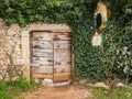 Old wooden door, stone wall with ivy and religious statue in Cres Royalty Free Stock Photo