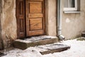 Old wooden door and thick pack of snow on the doorstep of a residential buildong near a water pipe in old town Royalty Free Stock Photo