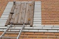 Old wooden door to the attic on rusty metal hinges, closed with a turntable lock and the top of metal ladder leaned to it Royalty Free Stock Photo