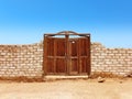 Old wooden door in white brick wall under blue sky in desert landscape. Constructions and architecture of the Egyptian desert Royalty Free Stock Photo