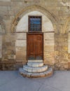 Old wooden door and window framed by arched bricks stone wall at the courtyard of al Razzaz historic house, Old Cairo, Egypt