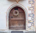 Old wooden door with wreath in painted wall, Brunico, South Tyrol, Italy Royalty Free Stock Photo