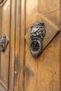 Old wooden doors with rings and old-fashioned vintage steel knocker handle shaped like a lion& x27;s head close up in Royalty Free Stock Photo