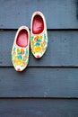 Old wooden Dutch shoes - klomps. A pair of klomps against the background of a wooden wall. Traditions of Holland. Background Royalty Free Stock Photo