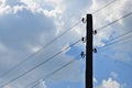 Old wooden electric pole for transmission of wired electricity on a background of a cloudy blue sky. Obsolete method of supplying Royalty Free Stock Photo