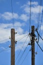 Old wooden electric pole for transmission of wired electricity on a background of a cloudy blue sky. Obsolete method of supplying Royalty Free Stock Photo