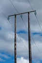 Old wooden electric post against blue sky and clouds Royalty Free Stock Photo