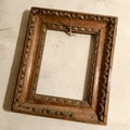 Old wooden empty photo frame hanging on the wall nailed rusty steel nail Royalty Free Stock Photo