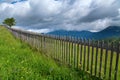 Old wooden fence across mountain meadow with a lonely tree. Royalty Free Stock Photo