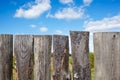Old wooden fence against a blue sky with clouds on a sunny day Royalty Free Stock Photo