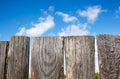 Old wooden fence against a blue sky with clouds on a sunny day Royalty Free Stock Photo