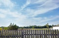 Old wooden fence against a blue sky with clouds on a sunny day Royalty Free Stock Photo