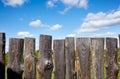 Old wooden fence against a blue sky with clouds on a sunny day Royalty Free Stock Photo