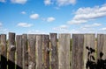 Old wooden fence against a blue sky with clouds on a sunny day Royalty Free Stock Photo