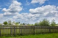 Old wooden fence against a blue sky with clouds on a sunny day Royalty Free Stock Photo