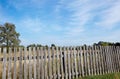 Old wooden fence against a blue sky with clouds on a sunny day Royalty Free Stock Photo