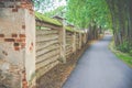 Old wooden fence in forest and asphalt road Royalty Free Stock Photo