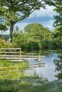 An old wooden fence half submerged into a pretty rural lake with reflections of the fence and surrounding trees