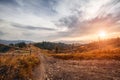 Old wooden fence, rural road and  top of mountain on horizon on sunset. summer landscape Royalty Free Stock Photo