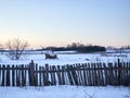 An old wooden fence and a snow-covered field, there is a small haystack on the field, snow is all around Royalty Free Stock Photo