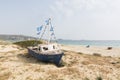 Old wooden fishing boat on the beach with Greek flags on the mast. Naxos island, Greece Royalty Free Stock Photo