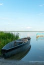 An old wooden fishing boat docked on a deserted sandy beach. View of a quiet and calm lake without ripples on the water. Royalty Free Stock Photo