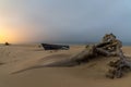 Old wooden fishing boat and driftwood on a beach after sunset with village lights behind Royalty Free Stock Photo