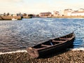 Old wooden fishing boat in focus. Town buildings out of focus in the background. River Corrib, Galway city, Ireland. Warm sunny Royalty Free Stock Photo