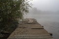 Old wooden fishing pier. Foggy morning on the lake Royalty Free Stock Photo