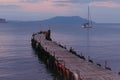 Old wooden fishing pier goes into the sea on sunset. Resort city Novyi Svet, Crimea Royalty Free Stock Photo