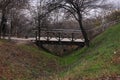 An old wooden footbridge over a ravine in the autumn foggy forest. Empty park near the river. Street travel wallpaper