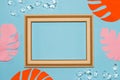 old wooden frame with blue copy space, around the frame blue wallpaper with orange-pink jungle leaves and gemstones Royalty Free Stock Photo