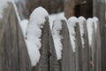 Old wooden garden fence covered with snow. Closeup.