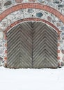 Old wooden gate with iron rivets in a granite wall in the wi