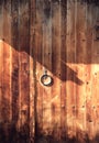 Old wooden gate with a metal door knob. Ring shape handle. Dark orange wooden background Royalty Free Stock Photo
