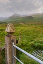 Old wooden gate pole in foreground and green field and mountains in the background. Low cloudy sky. Connemara, Ireland Royalty Free Stock Photo