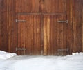 Old wooden gates, iron hinges in snow. Faded, unpainted gates, Royalty Free Stock Photo