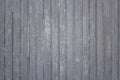 old wooden gray fence made of planks with peeling paint, cracks and white spots. vertical lines. rough surface texture Royalty Free Stock Photo