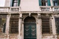 Closeup of the facade of a building, on the streets of Venice, Italy. Antique wooden green door. Forged patterns on a Royalty Free Stock Photo