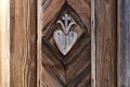 old wooden hart with cross pattern carved on wayside shrine door Royalty Free Stock Photo